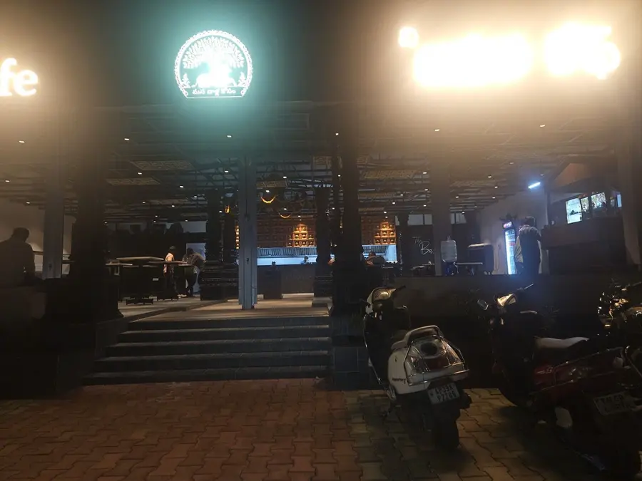 The dining hall at night, the illuminated Nandi roundel above the carved pillars.