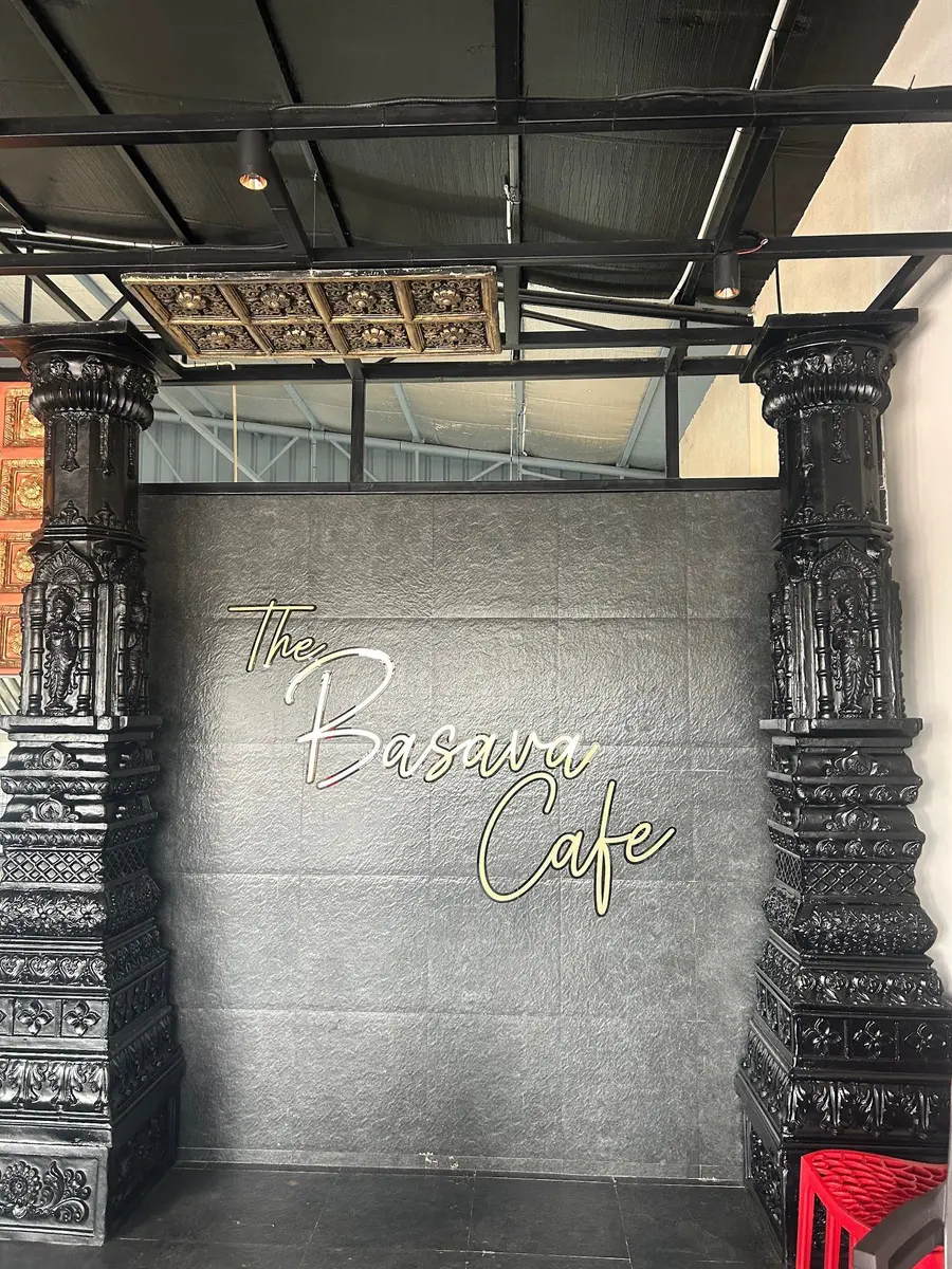 The cafe's name in gold neon script on polished black granite, framed by two carved pillars.